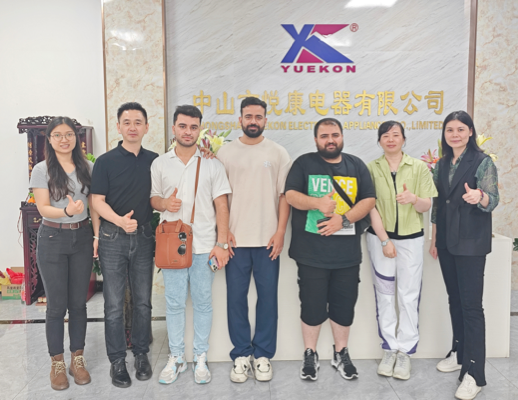 Empleados de Zhongshan Yuekon Electrical Appliances Co., Limited y clientes internacionales posan juntos, simbolizando una relación comercial exitosa y colaborativa.